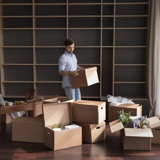 Homme portant des cartons dans un salon pendant une journée de déménagement.
