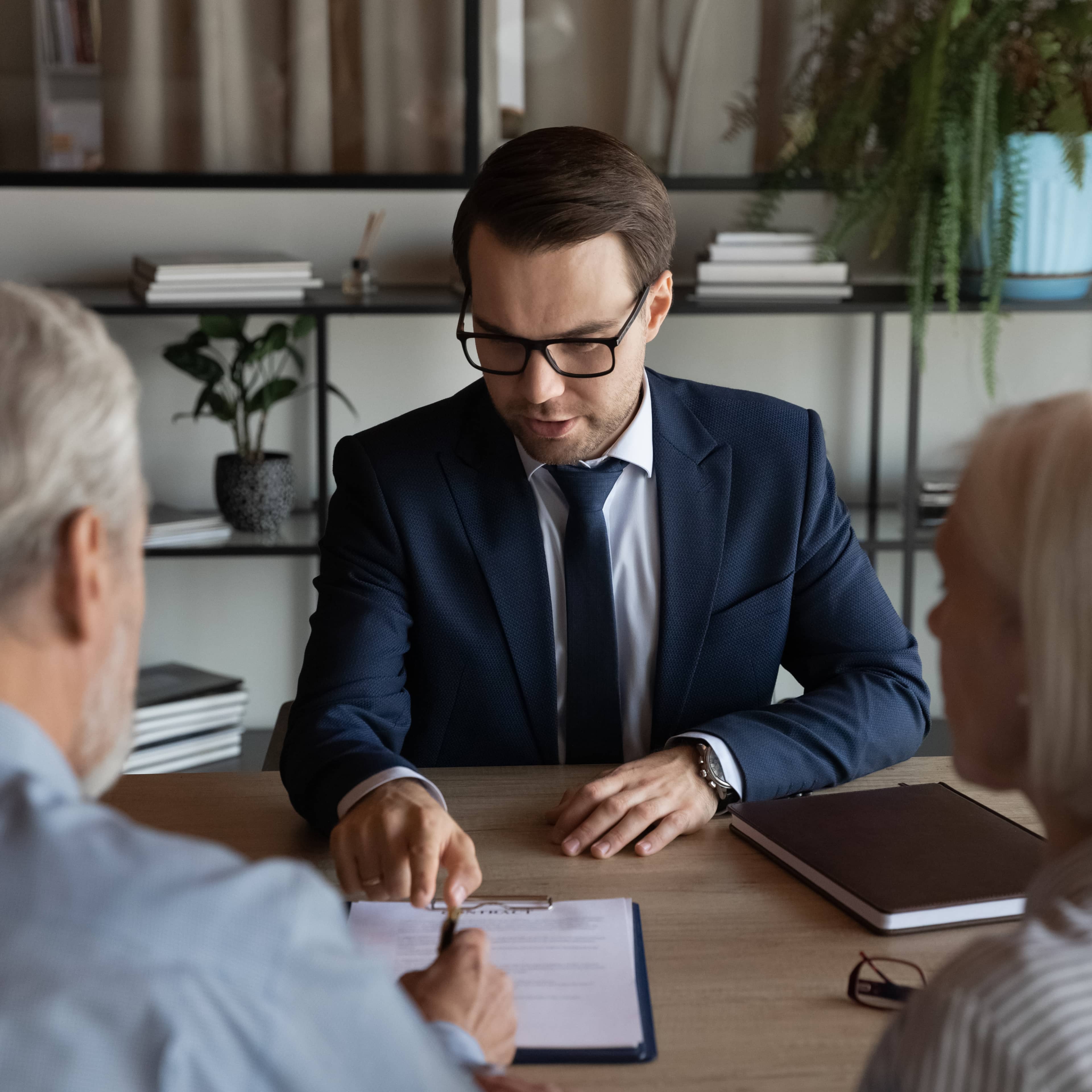 Notaire donnant des conseils immobiliers à deux clients et expliquant les documents juridiques.