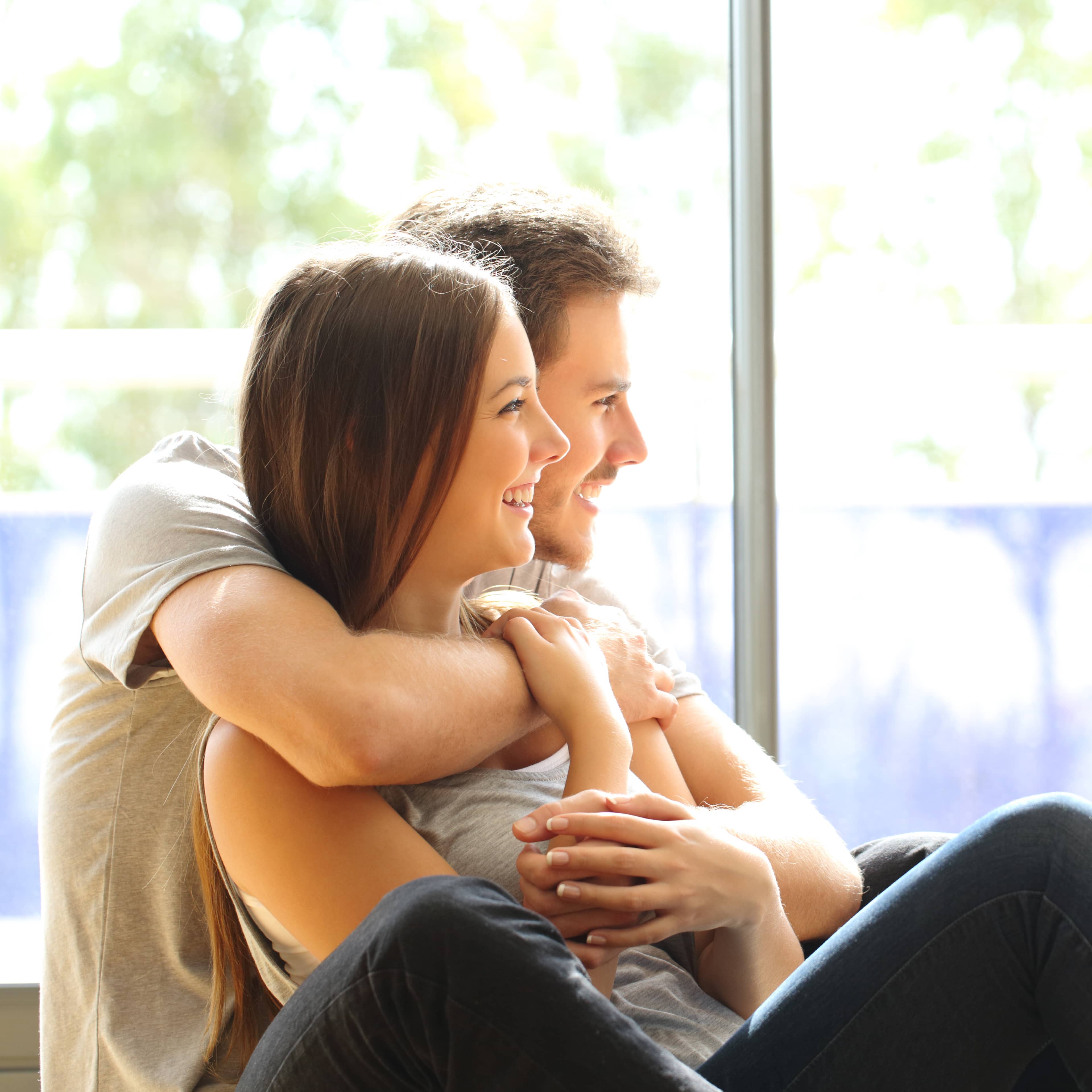 Couple dans leur nouvelle maison, regardant par la fenêtre