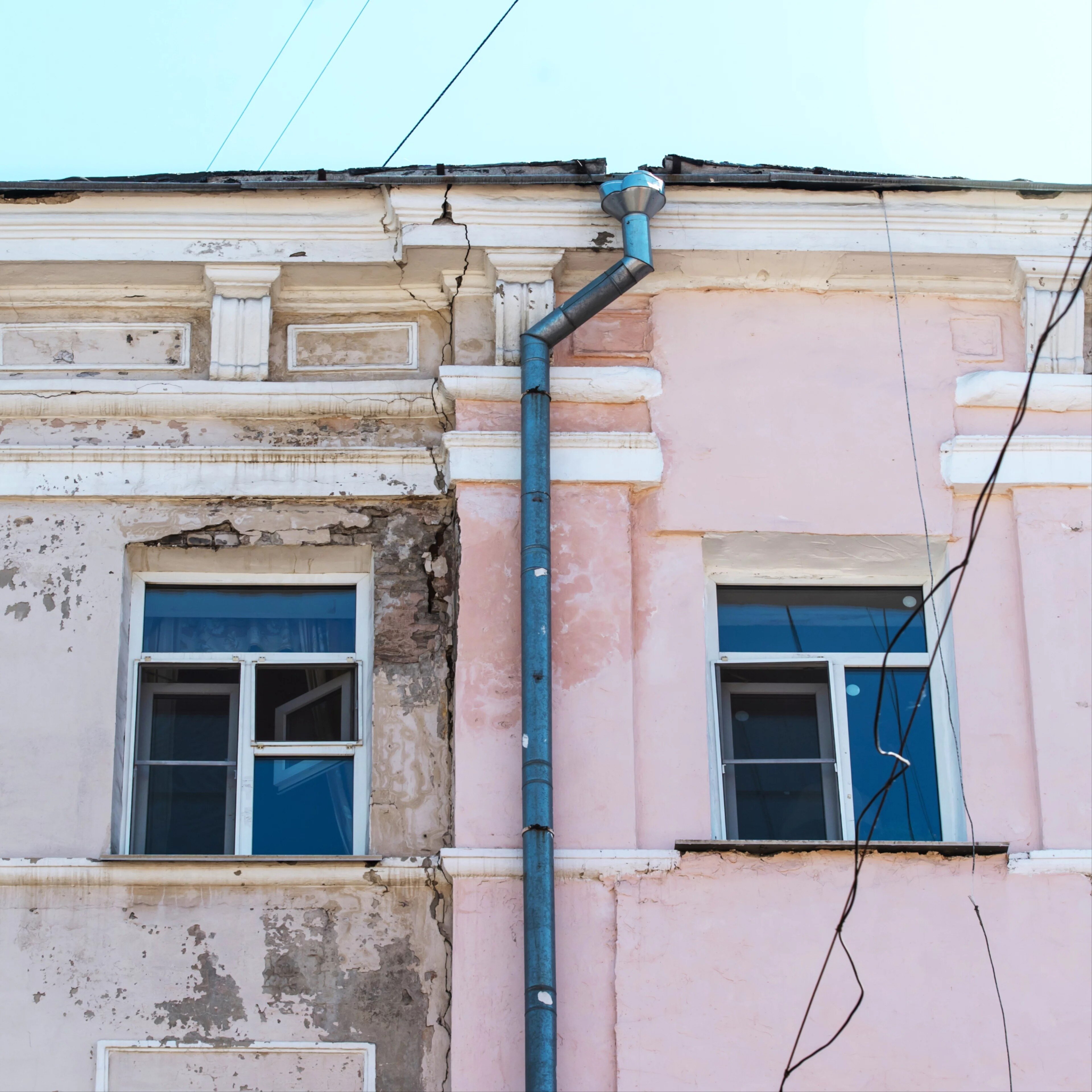 Fragment d'un bâtiment historique avec des fissures et une façade abîmée.