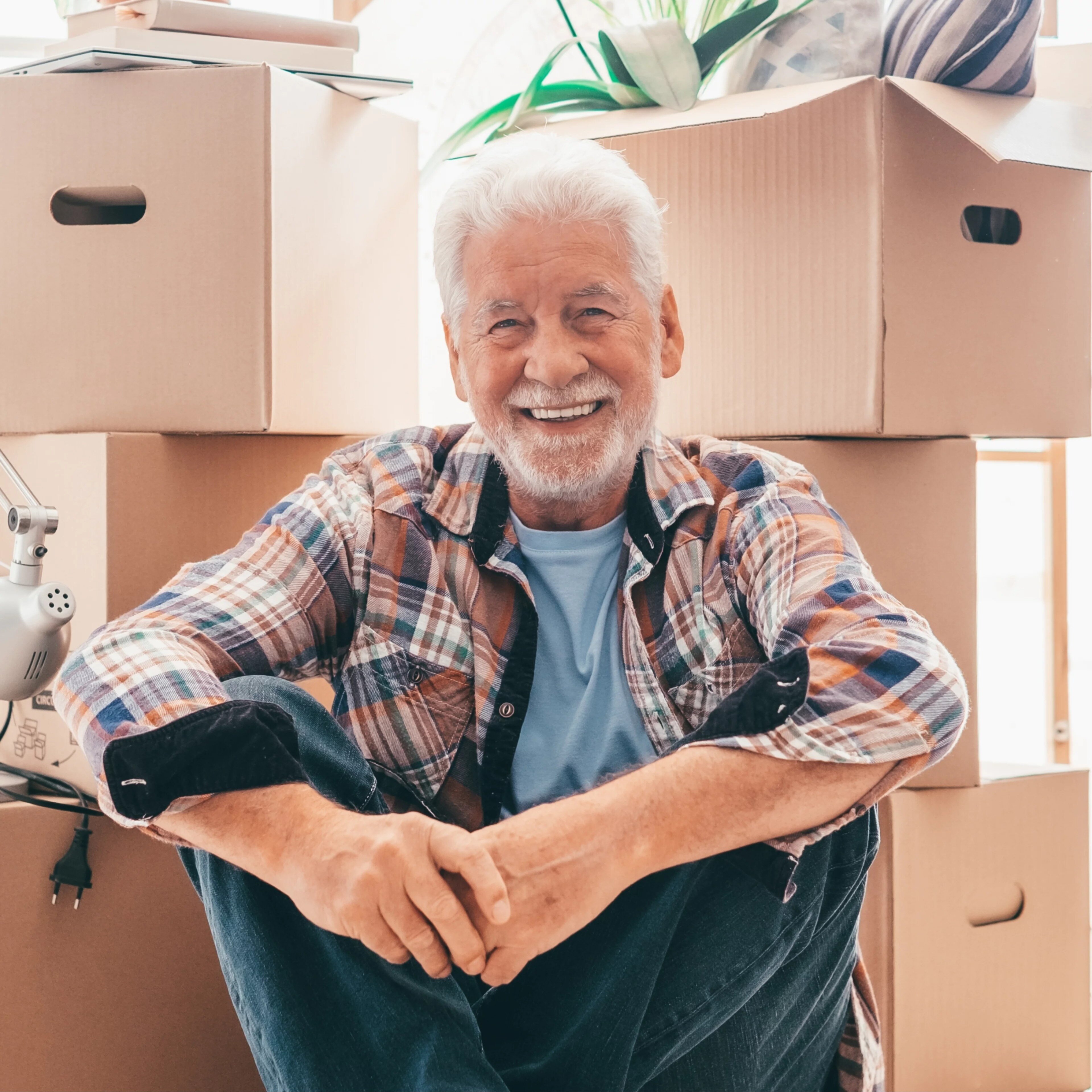 Joyeux homme âgé se reposant devant ses cartons le jour du déménagement.