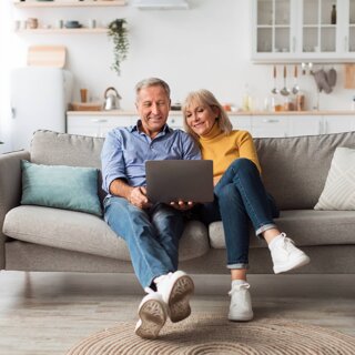 Couple senior parcourant internet sur ordinateur lisant les nouvelles en ligne