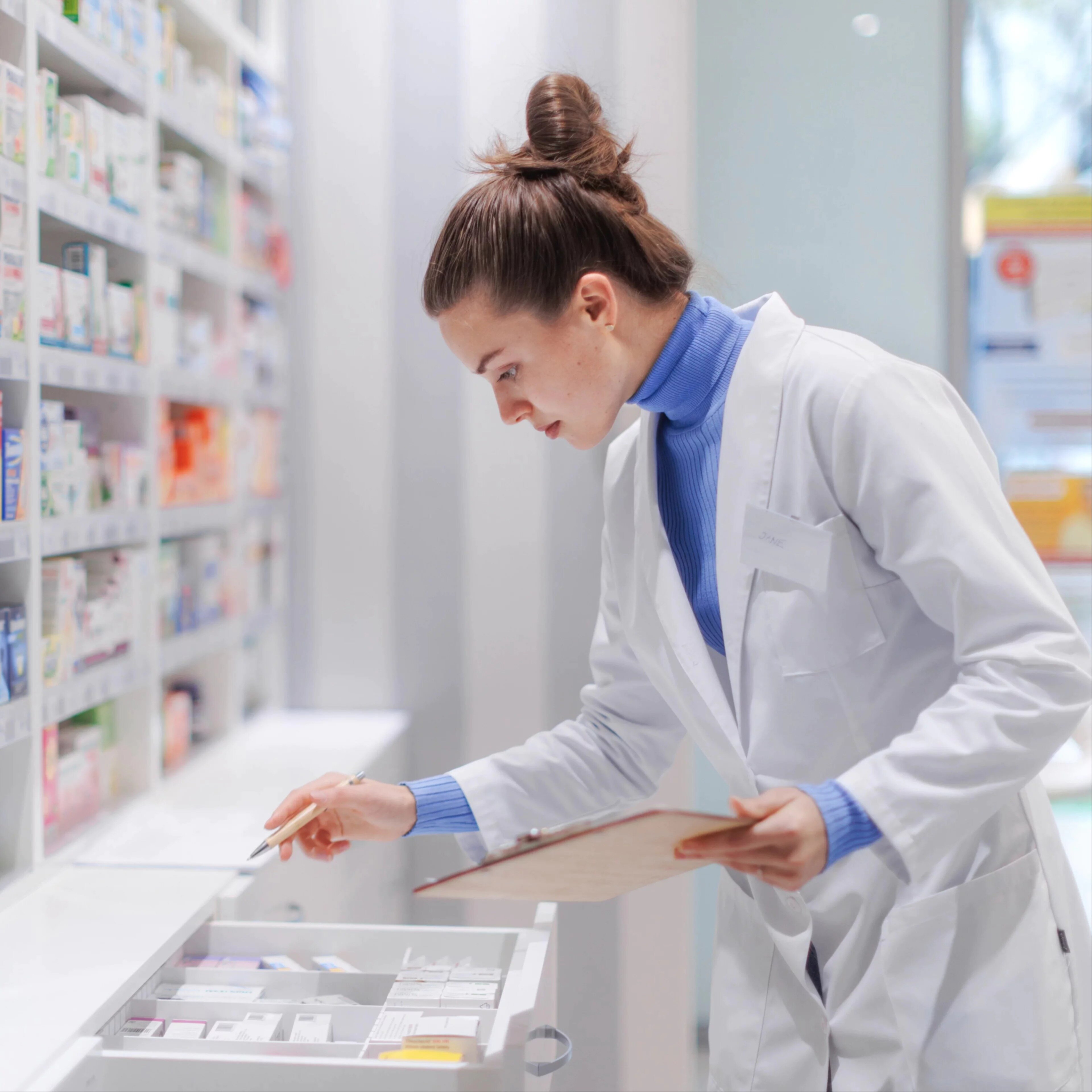 Jeune pharmacienne vérifiant le stock de médicaments en pharmacie.