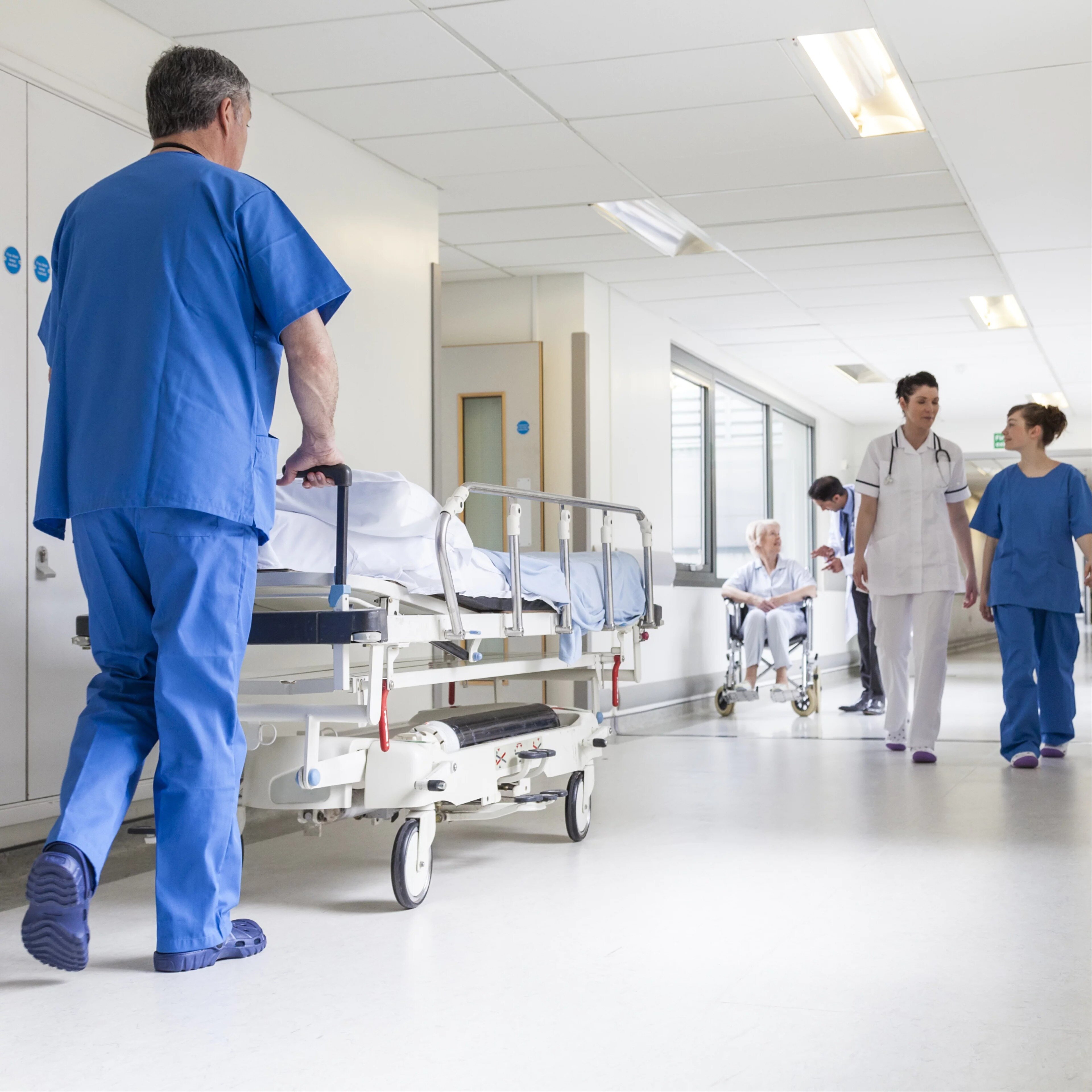 Un infirmier pousse un lit de brancard dans le couloir de l'hôpital avec des médecins