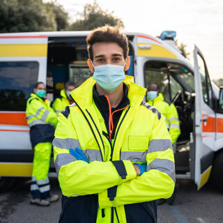Jeune homme avec un masque facial aux premiers soins devant ses collègues en ambulance