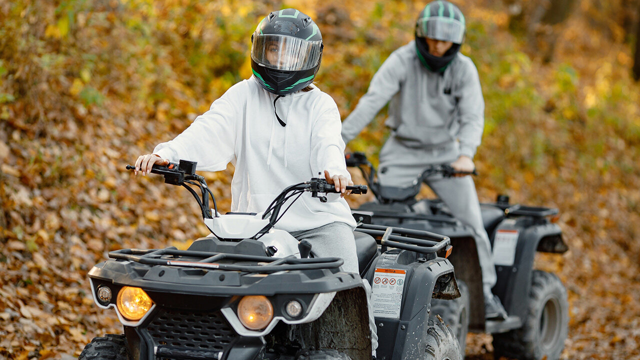 Deux personnes sur un quad, dans la forêt