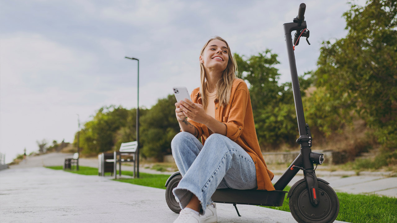 Jeune femme assise sur une trottinette
