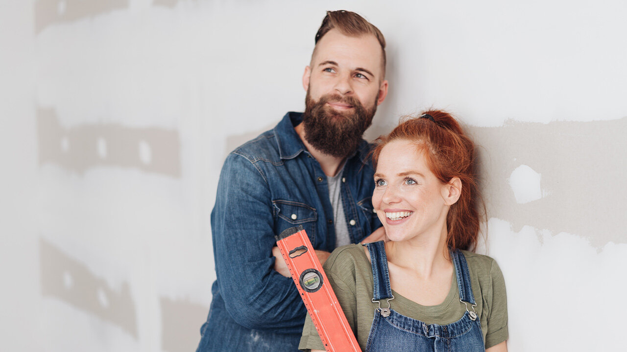 Jeune coupe devant un mur prêt à être repeint