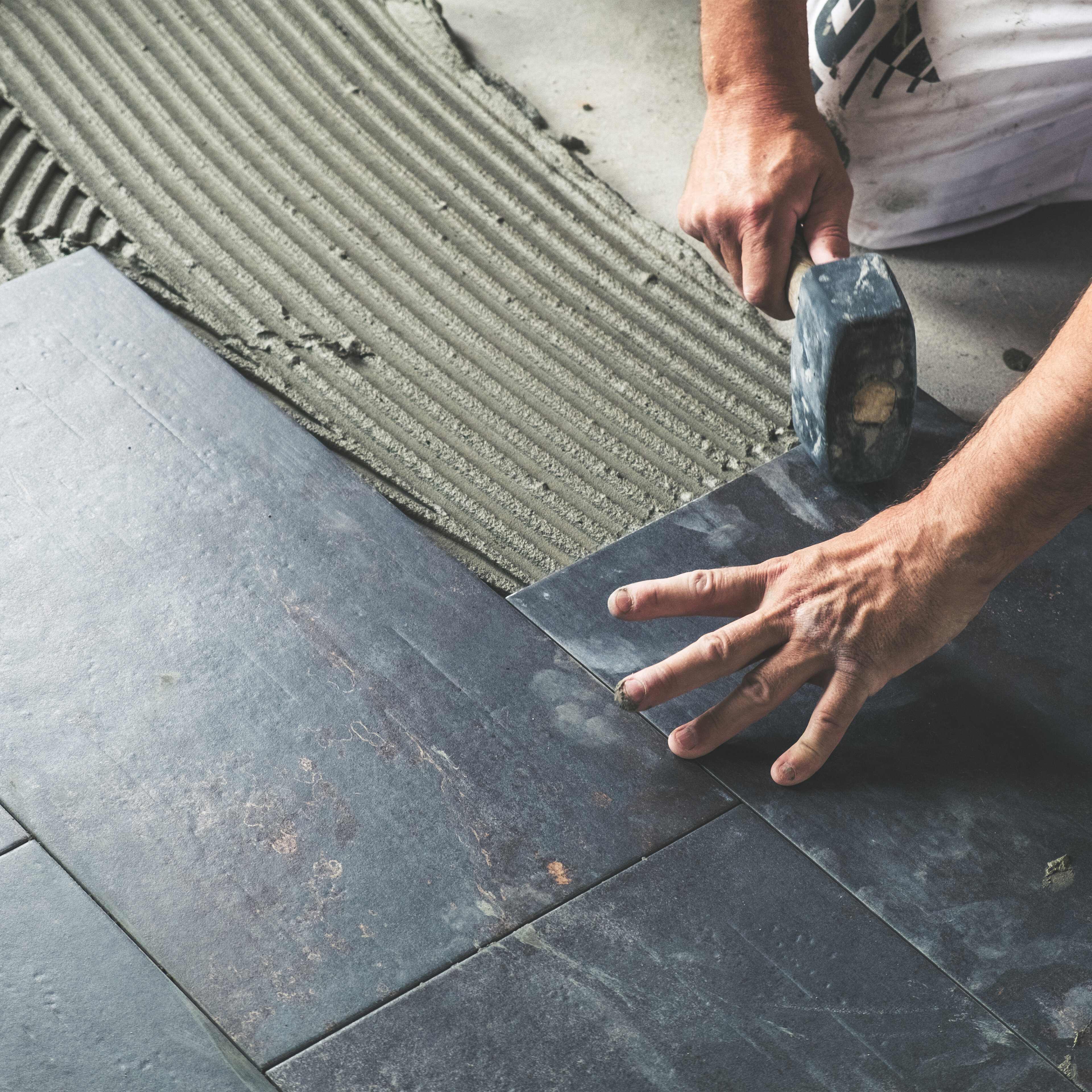 artisan qui installe du carrelage au sol